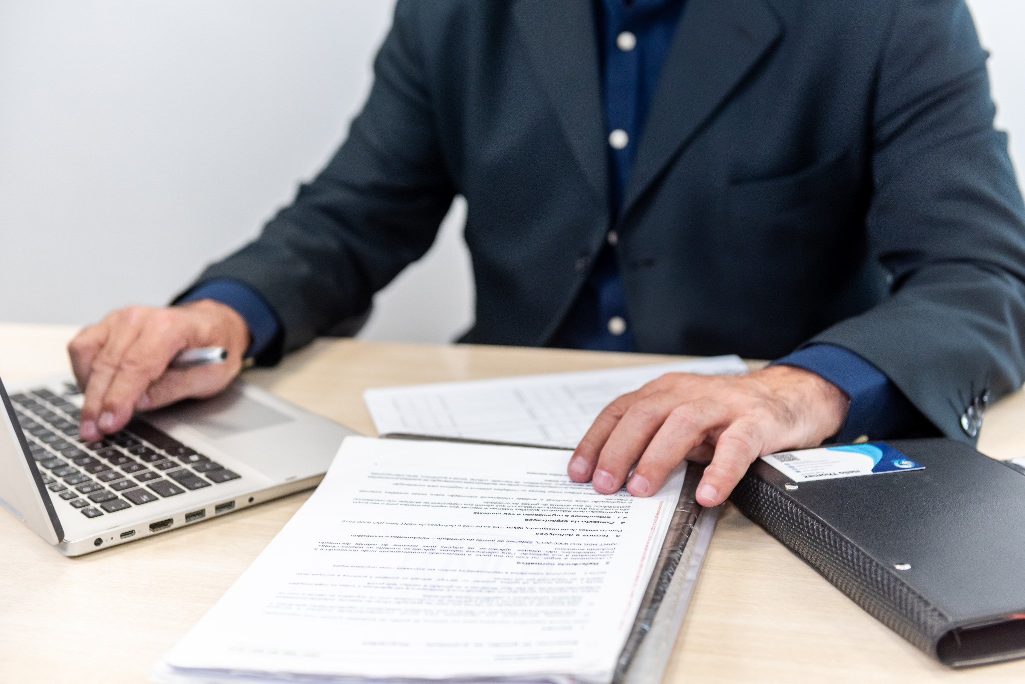 Consultor analisando documentos ao lado de um notebook